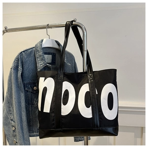 Détail d'un grand sac cabas noir avec imprimé hoco et une veste en jean assortie