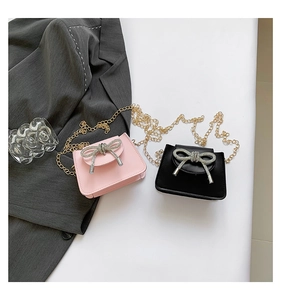 Close-up of stylish mini chain bags featuring sparkling rhinestone bow and gold metal strap