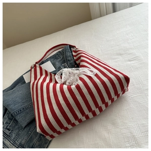 Detail of red and white striped canvas bucket bag with elegant white lace bow decoration