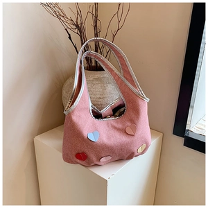 Detailed shot of pink canvas tote bag featuring colorful heart patches and silver trim