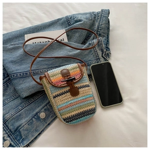 Detail of a rainbow straw phone bag with colorful woven stripes and a brown leather strap