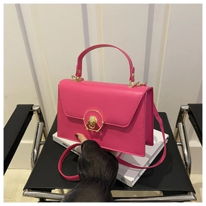 Close-up of rose pink crossbody bag with gold round metal lock and envelope flap cover