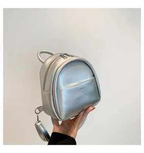 Détail d'un mini sac à dos en cuir argenté métallisé avec petite pochette ronde zippée