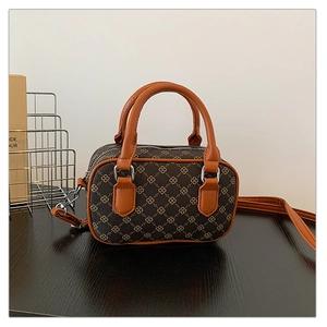 Detail of a brown mini Boston bag featuring monogram canvas and orange faux leather handles