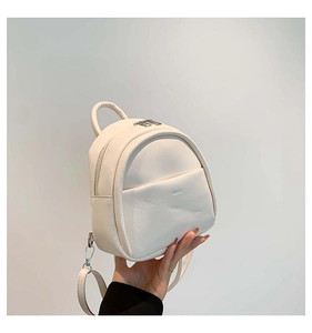 Gros plan d'un mini sac à dos blanc crème minimaliste avec fermeture éclair en métal