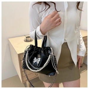 Détail du sac à main plissé noir avec chaîne en perles et papillon argenté élégant