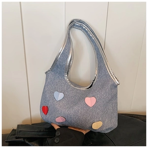 Detail of light blue denim tote bag with colorful heart patches and silver trim finish