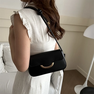 Sac sous le bras noir en cuir avec boucle dorée et bandoulière nouée sur un mannequin
