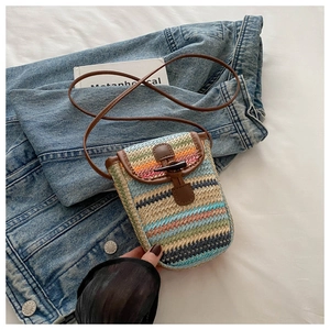 Detail of colorful rainbow straw weave phone bag with brown leather trim and toggle closure