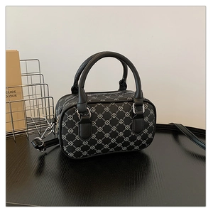 Close-up of black handbag with white infinity pattern, featuring metal zip and handles