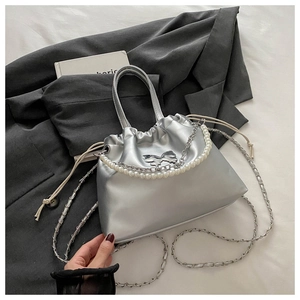 Détail du sac plissé argenté métallisé avec nœud papillon et chaîne de perles