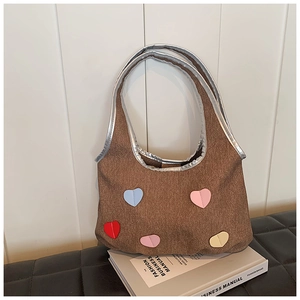 Close-up of brown denim bucket bag featuring colorful heart patches and silver metallic handles
