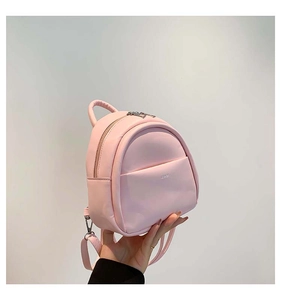 Détail d'un mini sac à dos rose avec des fermetures éclair argentées et une poignée