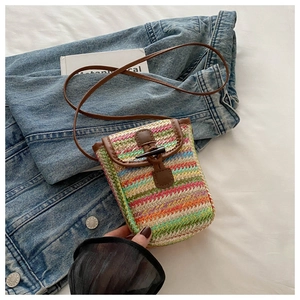Detail of hand-woven straw crossbody bag with colorful wave patterns and retro horn buckle