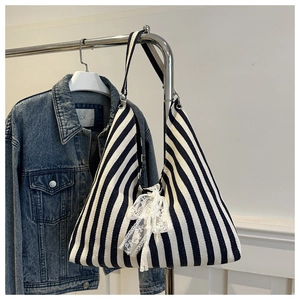 Detail view of blue striped canvas tote bag with a white lace bow and shoulder strap