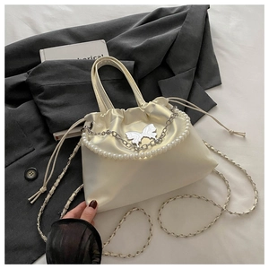Détail du sac en satin blanc cassé avec chaîne en perles et ornement de papillon argenté