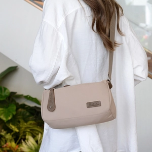 Beige waterproof nylon crossbody bag with brown leather trim and wide webbing strap
