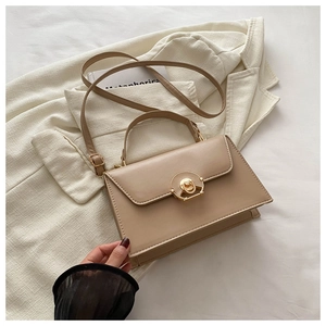Detail of the chic beige shoulder bag featuring a unique gold metal buckle and smooth leather