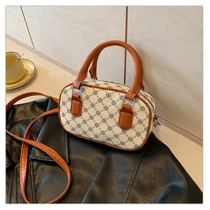 Detail shot of the chic monogram print and tan leather handles on the ivory crossbody bag