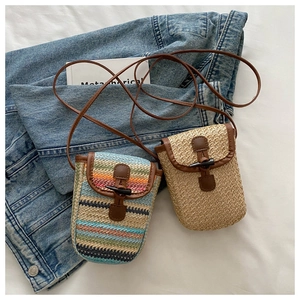 Close-up of handmade woven straw mini bags with rainbow stripes and leather strap detail