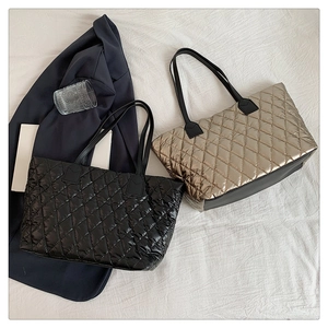 Flat lay of large quilted tote bags in black and champagne gold with diamond stitching