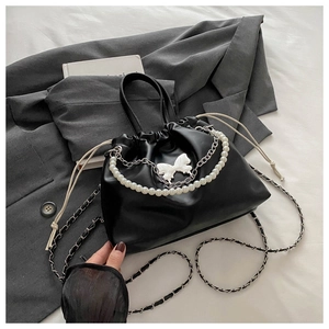 Vue détaillée d'un sac seau noir avec cordon, chaîne en perles et nœud décoratif