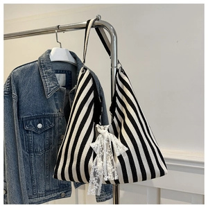 Close-up of black and white striped canvas tote bag with a decorative lace bow detail