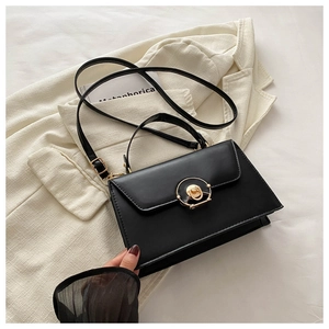 Detail of black leather handbag with a round gold rotating lock and adjustable strap