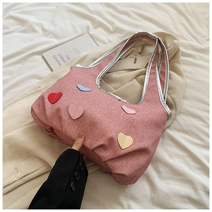 Detailed close-up of pink fabric tote bag featuring colorful heart patches and silver trim