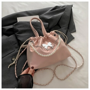 Détail d'un sac bourse en satin rose avec chaîne de perles et papillon argenté poli