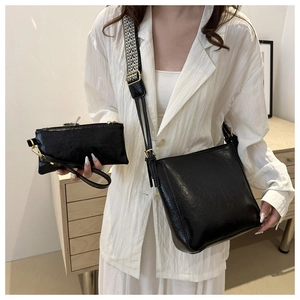 Detail of black textured faux leather tote with woven strap on a white blazer