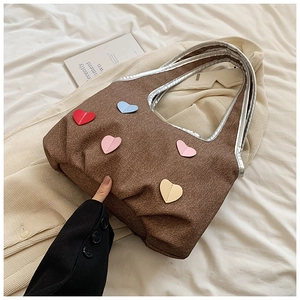 Detail of canvas tote bag with colorful heart patches and silver metallic handles