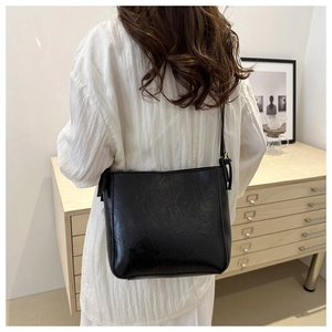 Detail view of the black textured leather tote bag worn by a model in a minimal setting