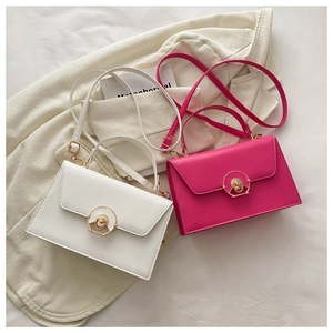 White and magenta leather crossbody bags with golden buckle on a textured background