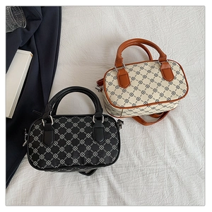 Close-up of printed pattern and metallic buckle detail on two small boston bags