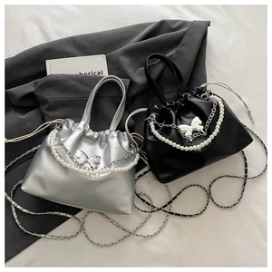 Détail de sacs plissés argent et noir avec boucle papillon et poignée en perles