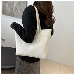 Detailed texture of white tote bag with gold rivet hardware and leather shoulder straps