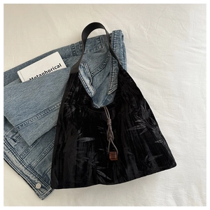 Détail du sac cabas en velours noir avec motifs de bambou gaufrés et boucle ambre élégante