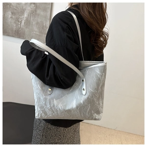 Silver wrinkled tote bag with dual shoulder straps shown on model in modern setting