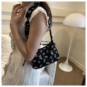 Dettaglio della borsa a tracolla in nylon nero con motivi a fiocco bianchi indossata