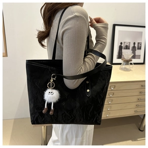 Detail of black pleated tote bag showing large capacity and cute plush monster pendant