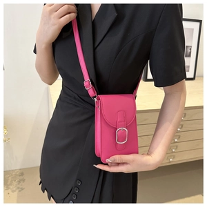 Detail of rose pink mini crossbody bag with leather texture and silver buckle on model