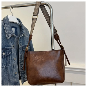 Close-up of retro brown PU leather crossbody bag with ethnic style woven wide strap