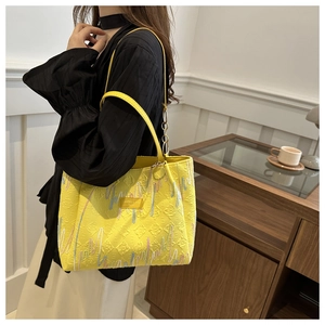 Close-up of a yellow canvas tote bag with colorful vertical stripes and diamond texture