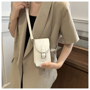 Detailed view of a white minimalist crossbody phone bag with silver buckle worn by a model