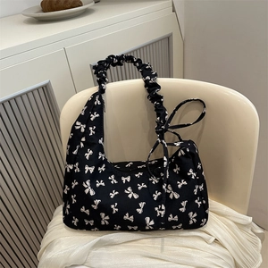 Black canvas shoulder bag featuring white bow prints and pleated cloud-style strap