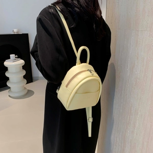 Mini sac à dos minimaliste jaune clair en similicuir, porté au dos pour échelle de taille