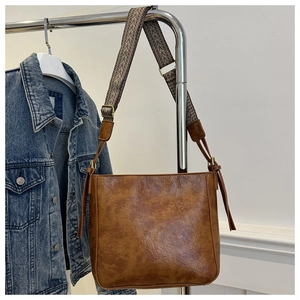 Detail of vintage brown PU leather tote bag with geometric pattern wide shoulder strap