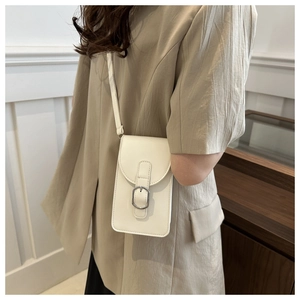 Detailed view of an off-white glossy mobile phone bag worn by a model in interior setting
