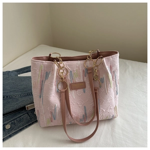 Detail of pink embroidered canvas tote with gold chain strap and leather patch